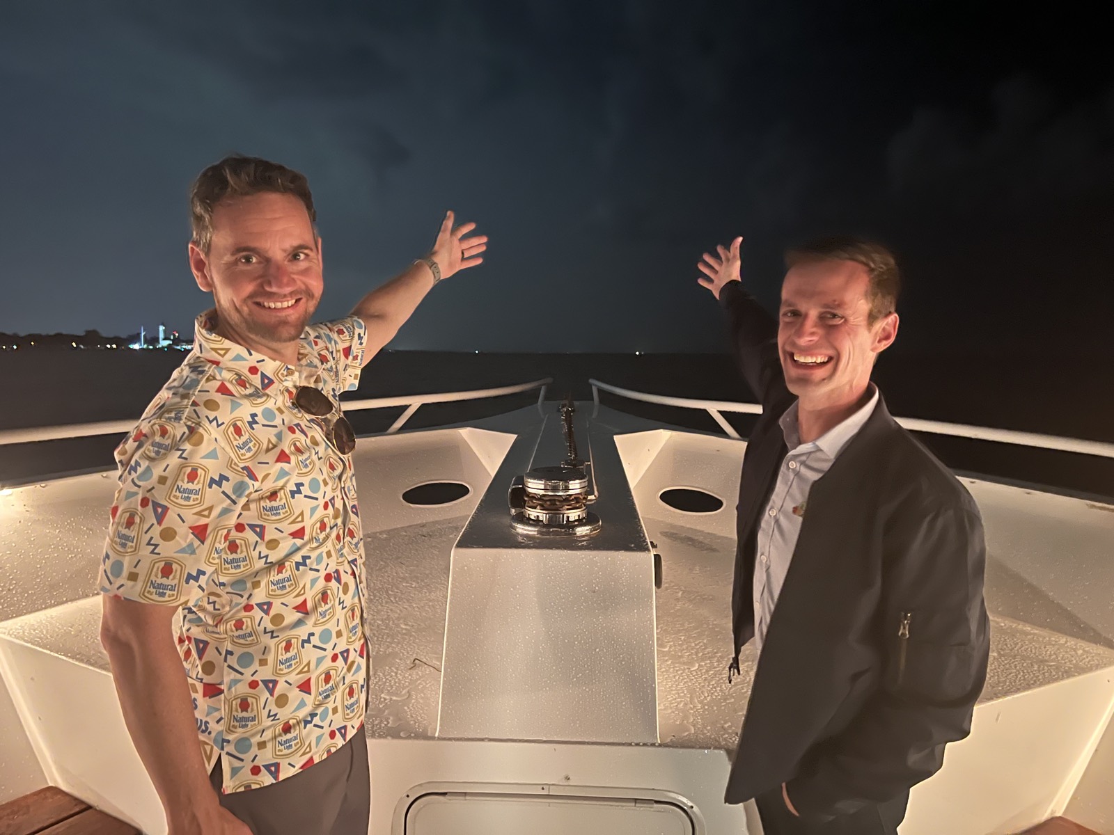 Pointing toward the horizon from the bow of a boat at night